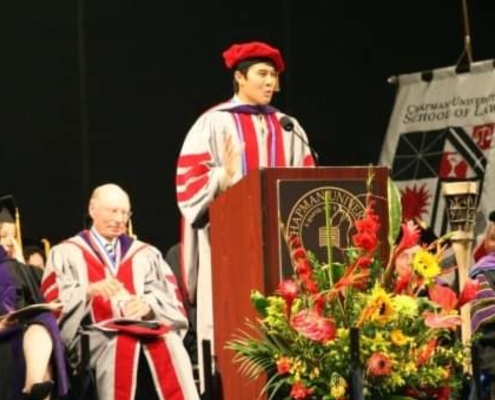 Photo of Deputy District Attorney Garret Wong giving a speech on stage during his law school graduation.