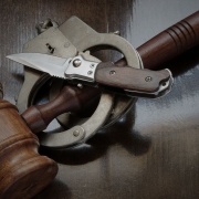Photo of a gavel with a knife and handcuffs.