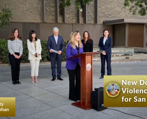 DA Summer Stephan speaks at a podium with city, county and state leaders standing behind her.