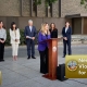 DA Summer Stephan speaks at a podium with city, county and state leaders standing behind her.