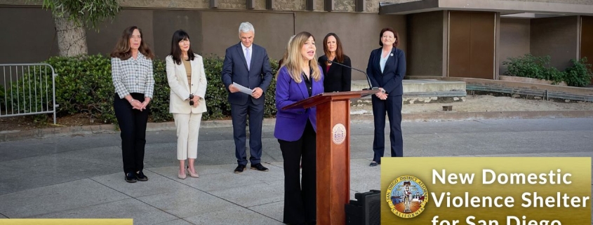 DA Summer Stephan speaks at a podium with city, county and state leaders standing behind her.