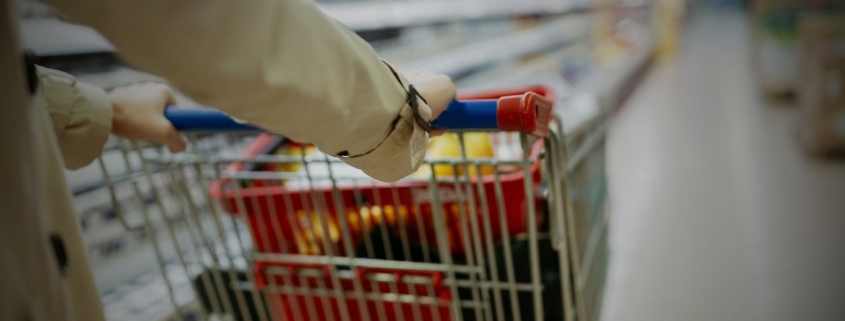 Woman pushing shopping cart in supermarket.