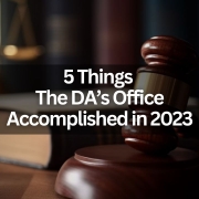 Text that says "5 Things the DA's Office Accomplished in 2023" with the background of a gavel, scales of justice and a few books on a table.