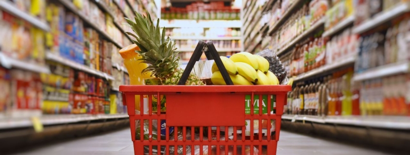 Photo of grocery basket on the floor of a food isle in a grocery store.