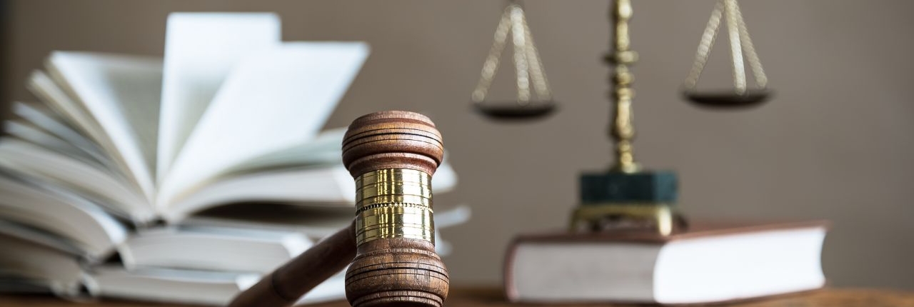 Photo of a gavel over law books and scales of justice.