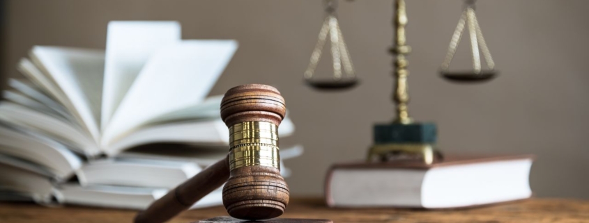 Photo of a gavel over law books and scales of justice.