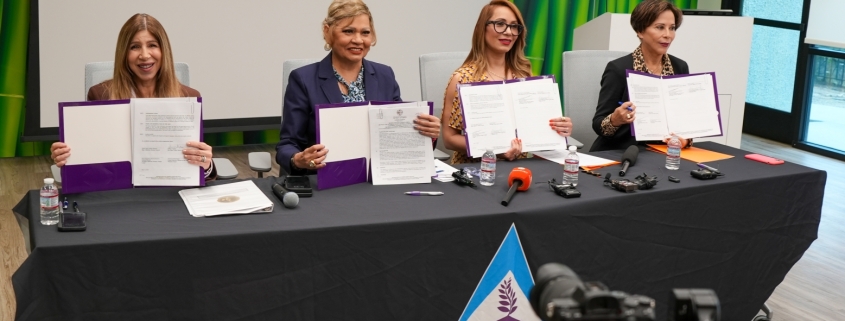 Photo of the four representatives holding up the MOU document, sitting at a table in One Safe Place: The South County Family Justice Center.