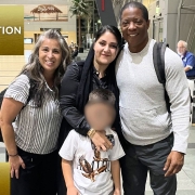 Photo of Child Abduction Unit team with recovered child at airport reunited with mother.