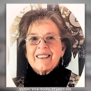 Smiling woman with short dark hair and glasses, wearing dangling earrings and a patterned top, photographed against a light background with a decorative circular frame.