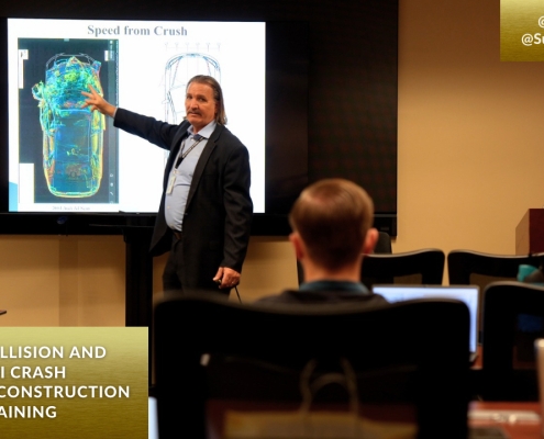 A man stands in front of a screen projector showing the image of a car to an audience in a classroom training room.